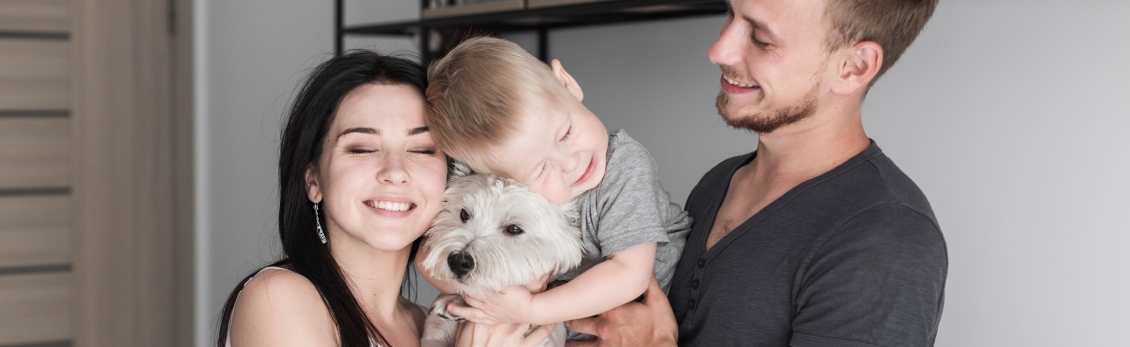 Famiglia che abbraccia un cagnolino bianco